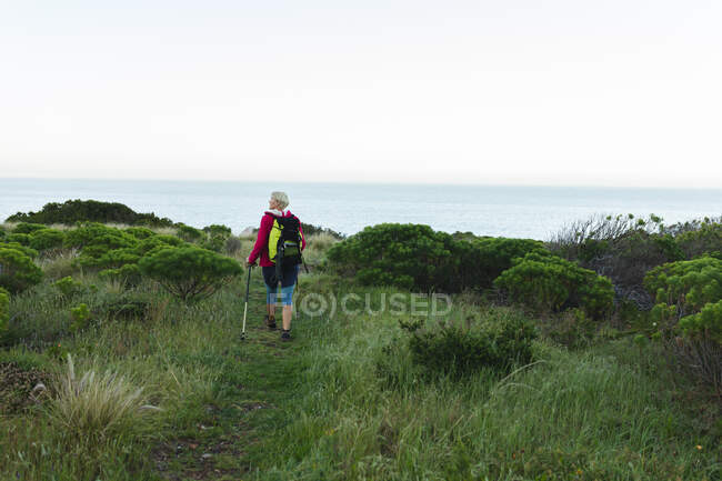 Senior woman spending time in nature, walking in mountains, looking around. healthy lifestyle retirement activity. — Stock Photo