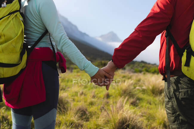 Pareja pasando tiempo en la naturaleza juntos, caminando por las montañas, tomados de la mano. - foto de stock