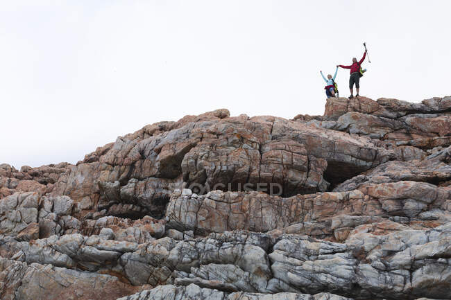 Старшая пара проводит время на природе вместе, гуляя в горах, держась за руки, поднимая руки. активный уход на пенсию. — стоковое фото