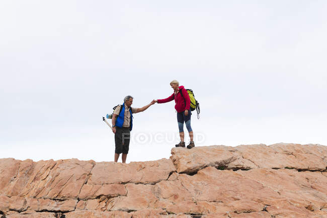 Старшая пара проводит время на природе вместе, гуляя в горах, держась за руки. активный уход на пенсию. — стоковое фото