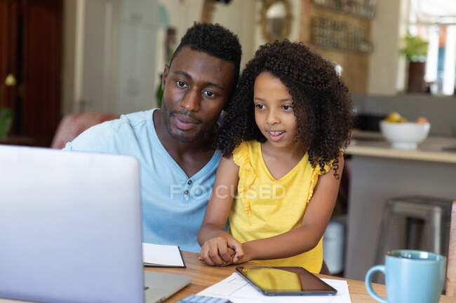 Afroamerikanische Vater und Tochter benutzen einen Laptop zu Hause und bleiben während der Sperrung zu Hause. Häusliches Leben und Leben in Quarantäne. — Stockfoto