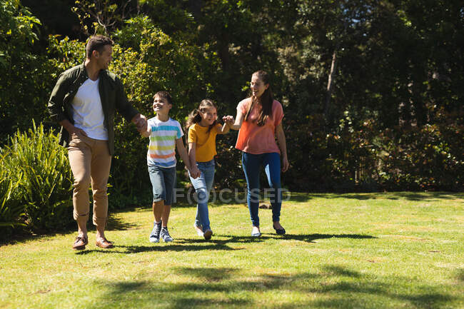 Kaukasische Familie, die an einem sonnigen Tag draußen spaziert, lächelt und Händchen hält. Qualität Lebensstil Familie Zeit zusammen während Coronavirus covid 19 Quarantäne Lockdown. — Stockfoto