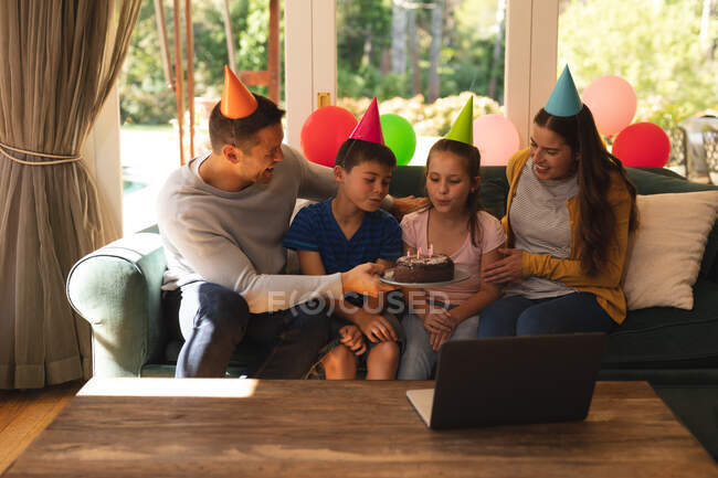 Kaukasische Familie, die zu Hause zusammen einen Geburtstag feiert, Partyhüte trägt und Kerzen bläst. Qualität der gemeinsamen Zeit bei Coronavirus covid 19 Quarantäne Lockdown. — Stockfoto