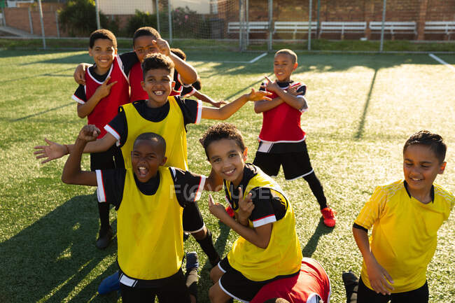 Fußballteam der multirassischen Jungen glücklich nach dem Gewinn eines Spiels, posierend mit Handzeichen. Sport und Sportveranstaltungen. — Stockfoto
