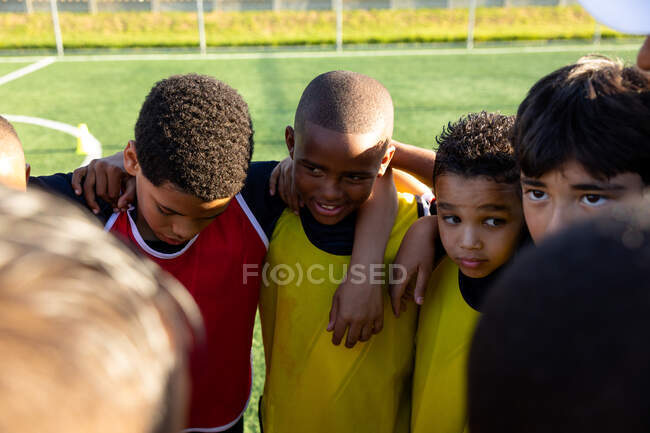 Squadra multirazziale di calcio maschile in piedi in un semicerchio, braccia sulle spalle, durante una partita. Sport ed eventi sportivi. — Foto stock