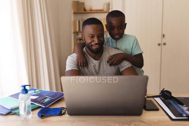 Африканський батько і син мають вдома відеобесіду на ноутбуці. Соціальна дистанція в корі 19 Коронавірус карантин. — стокове фото