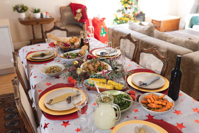 Table décorée pendant la période de Noël, avec de nombreux plats, bouteille de vin et jus couché sur une table. — Photo de stock