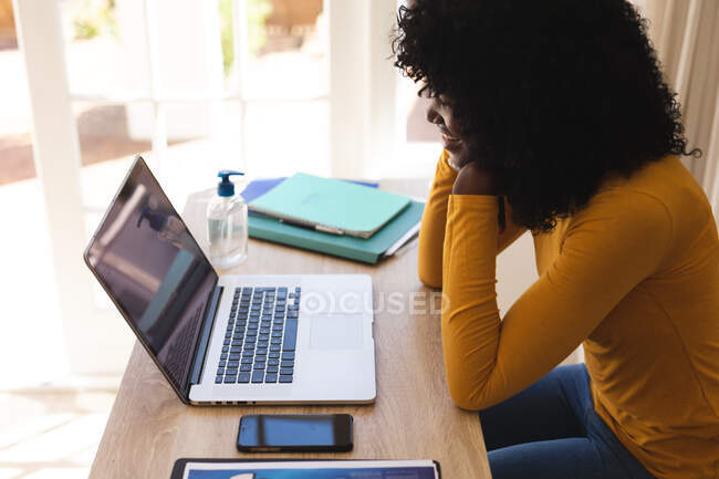 Donna afroamericana che ha una video chat sul computer portatile mentre lavora da casa. distanza sociale durante covid 19 isolamento di quarantena coronavirus. — Foto stock