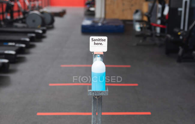 View of sanitizer foot dispenser stand with sanitize here text in the gym. social distancing quarantine lockdown during coronavirus pandemic — Stock Photo