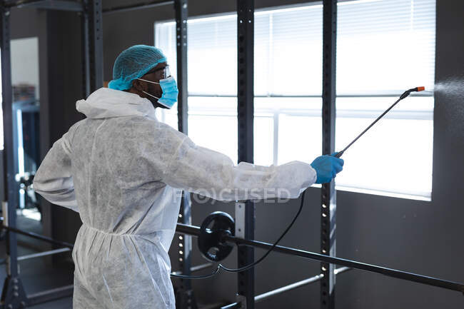 Männliche Arbeiter tragen Schutzkleidung und Mundschutz und reinigen die Turnhalle mit Desinfektionsmittel. Soziale Distanzierung von Quarantäne während der Coronavirus-Pandemie — Stockfoto
