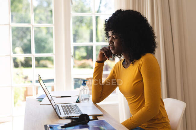 African american woman having a video chat on laptop while working from home. social distancing during covid 19 coronavirus quarantine lockdown. — Stock Photo