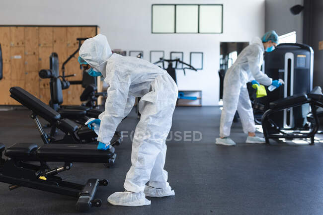Team of workers wearing protective clothes and face masks cleaning the gym using disinfectant. social distancing quarantine lockdown during coronavirus pandemic — Stock Photo