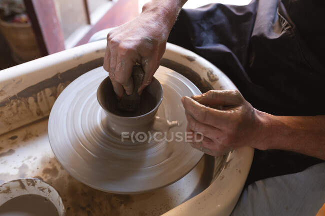 Potier masculin travaillant dans un atelier de poterie. travailler à une roue de potiers. petite entreprise créative pendant la pandémie de coronavirus covid 19. — Photo de stock