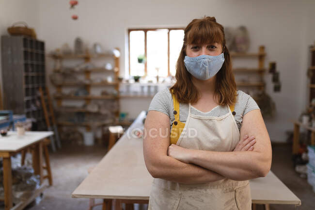Портрет белой женщины в маске для лица в мастерской керамики. малый творческий бизнес во время пандемии коронавируса ковида 19. — стоковое фото