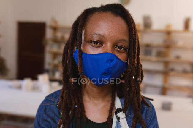 Портрет женщины смешанной расы в маске для лица в мастерской керамики. малый творческий бизнес во время пандемии коронавируса ковида 19. — стоковое фото