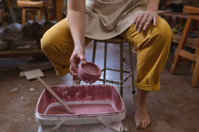 Ceramista donna che lavora nello studio di ceramica. dipingere una ciotola. piccola attività creativa durante covid 19 coronavirus pandemia. — Foto stock