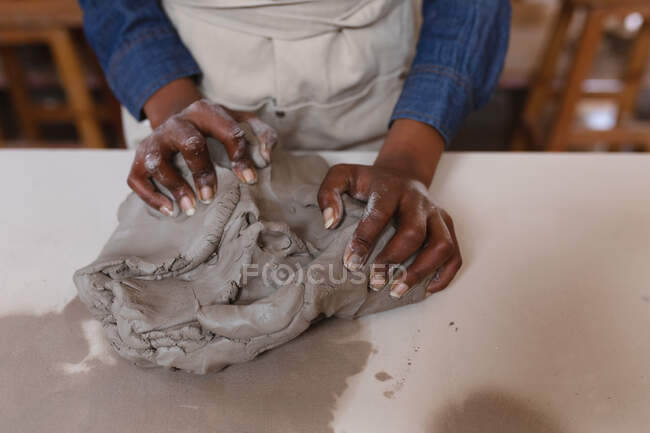 Primo piano di ceramista donna che lavora nello studio di ceramica. indossando grembiule, lavorando ad un tavolo di lavoro. piccola attività creativa durante covid 19 coronavirus pandemia. — Foto stock