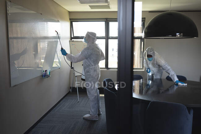 Equipo de trabajadores de la salud que usan ropa protectora en la oficina usando desinfectante. limpieza y desinfección prevención y control de la epidemia de covid-19 - foto de stock