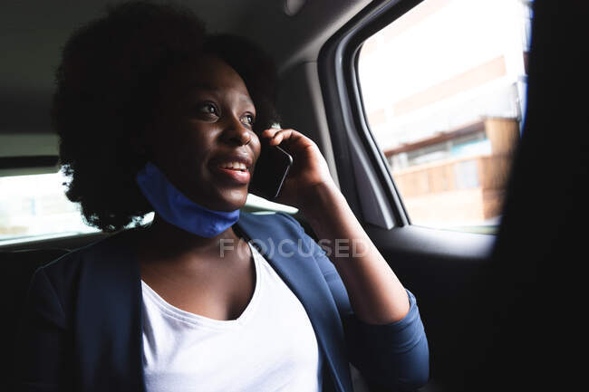 Африканська американка в масці на обличчі розмовляє на смартфоні. і десь у місті під час коронавірусної пандемії.. — стокове фото