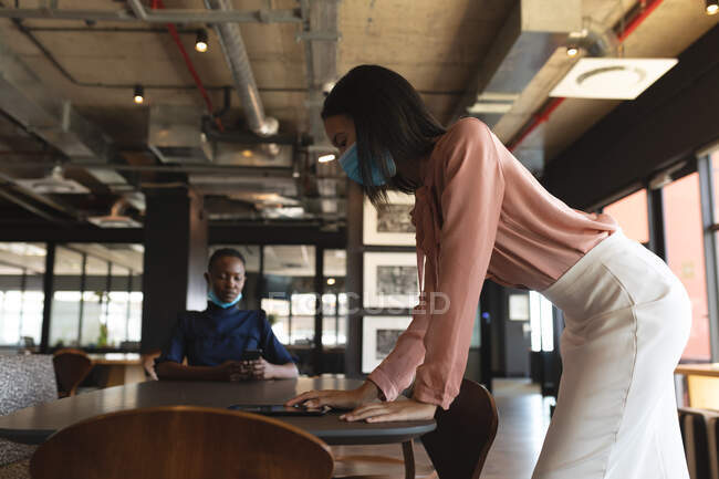 Азійка, одягнена в маску обличчя, користується цифровим планшетом у сучасному офісі. Відстань до карантину під час пандемії коронавірусу — стокове фото
