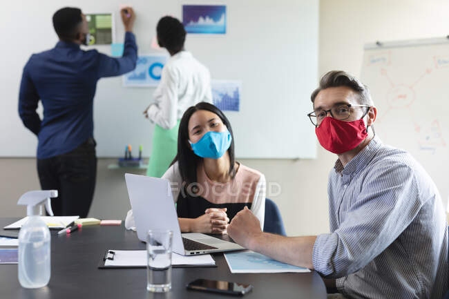 Портрет различных коллег мужского и женского пола в масках в офисе социального дистанционного карантина во время пандемии коронавируса. — стоковое фото