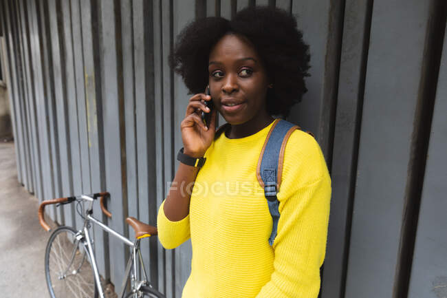 Africano americano mulher falando ao telefone em uma rua fora e sobre na cidade durante covid 19 coronavirus pandemia. — Fotografia de Stock