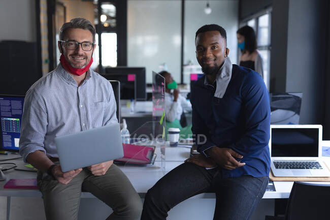 Portrait of diverse male colleagues with face masks around their neck at modern office. social distancing quarantine lockdown during coronavirus pandemic — Stock Photo