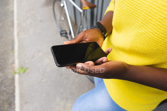 Donna afroamericana utilizzando smartphone su una strada fuori e in giro per la città durante covid 19 pandemia coronavirus. — Foto stock