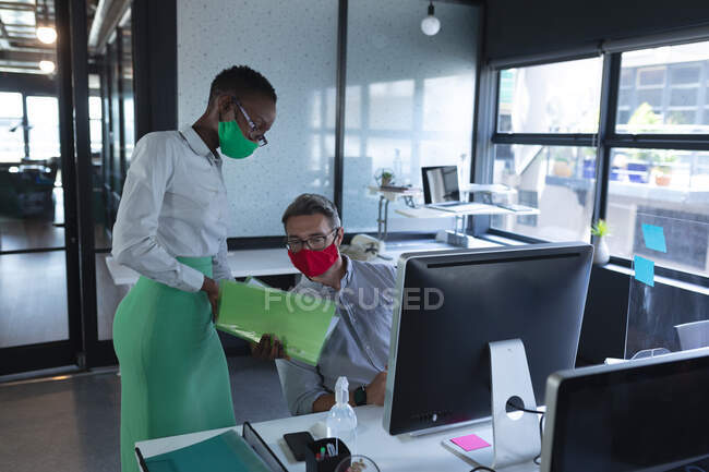 Diversos homens e mulheres usando máscaras faciais discutindo no escritório. bloqueio de quarentena por distanciamento social durante a pandemia do coronavírus. — Fotografia de Stock