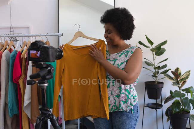 Afro-americana vlogger feminino gravando um vídeo em guarda-roupa. mostrando roupas para a câmera. comunicação de tecnologia de auto-isolamento em casa durante a pandemia do coronavírus covid 19. — Fotografia de Stock