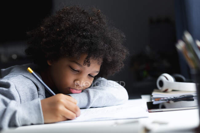 Mixed race girl lying on a desk drawing in notebook. self isolation quality family time at home together during coronavirus covid 19 pandemic. — Stock Photo