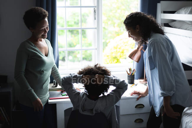 Mixed race lesbian couple talking with daughter sitting at desk. self isolation quality family time at home together during coronavirus covid 19 pandemic. — Stock Photo