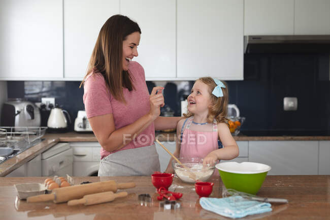 Кавказская мать и дочь развлекаются на кухне. наслаждаясь временем дома во время коронавирусного ковида 19 пандемического блокирования. — стоковое фото