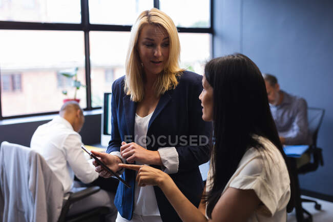 Diverse women working in creative office, discussing using digital tablet. modern office business teamwork brainstorming. — Stock Photo