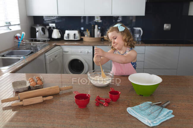 Chica caucásica divirtiéndose horneando en la cocina mezclando ingredientes. disfrutando de tiempo de calidad en casa durante coronavirus covid 19 pandemia de bloqueo. - foto de stock