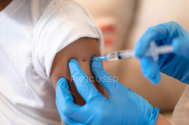 Fille qui se fait vacciner contre la grippe par un médecin portant des gants chirurgicaux. auto-isolement à la maison pendant une pandémie de coronavirus covid 19 — Photo de stock
