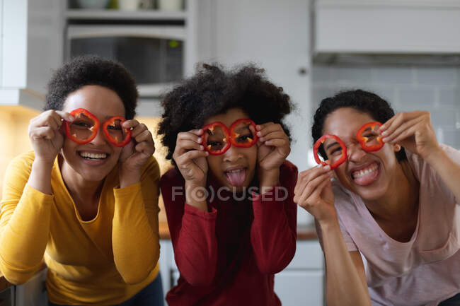 Portrait of mixed race lesbian couple and daughter having fun with food in kitchen. self isolation quality family time at home together during coronavirus covid 19 pandemic. — Stock Photo