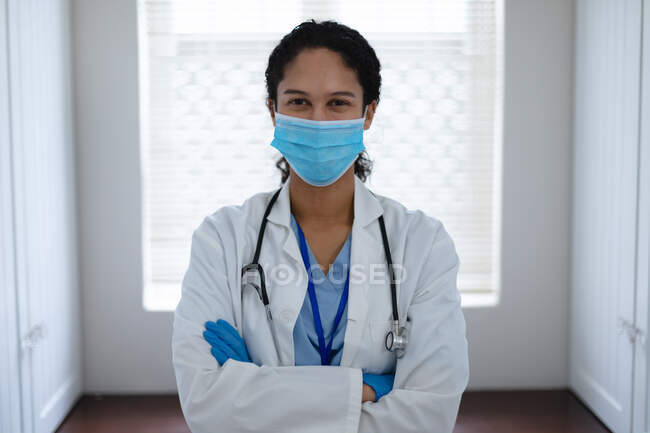 Portrait of mixed race female doctor looking at camera. self isolation quality time at home together during coronavirus covid 19 pandemic. — Stock Photo