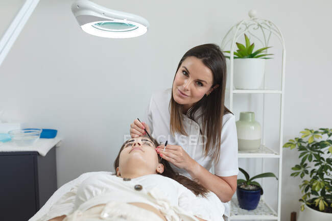 Caucasian woman lying back while beautician dyes her eyebrows. customer enjoying treatment at a beauty salon. — Stock Photo