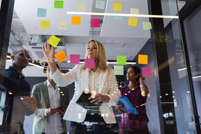 Diversi uomini d'affari che fanno brainstorming con il consiglio di vetro in ufficio. moderni professionisti del business creativo incontro sul posto di lavoro. — Foto stock