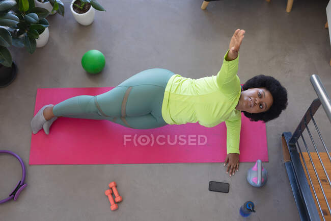 High angle view of african american woman lying on exercise mat working out. self isolation fitness at home during coronavirus covid 19 pandemic. — Stock Photo
