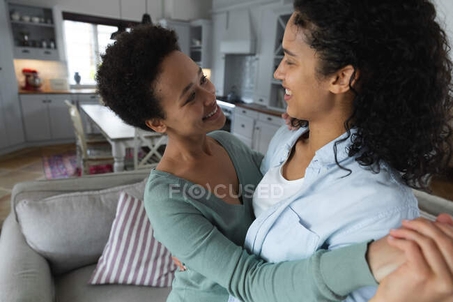 Romantic mixed race lesbian couple dancing in sitting room. self isolation quality time at home together during coronavirus covid 19 pandemic. — Stock Photo