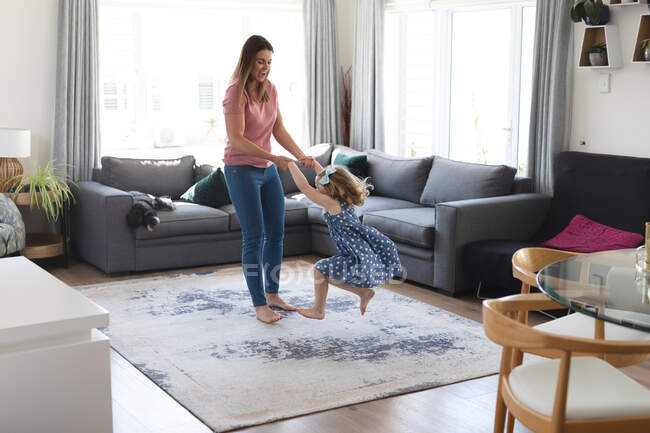 Mãe e filha caucasiana se divertindo dançando na sala de estar. desfrutando de tempo de qualidade em casa durante coronavírus covid 19 bloqueio pandêmico. — Fotografia de Stock