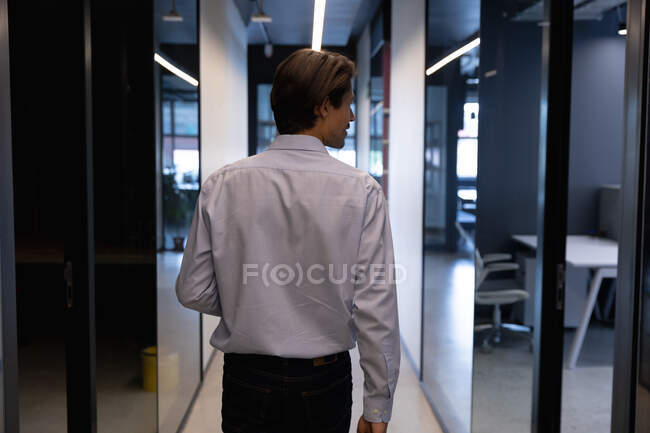 Homem de negócios caucasiano andando segurando um laptop em um escritório moderno. negócio moderno escritório tecnologia do local de trabalho. — Fotografia de Stock