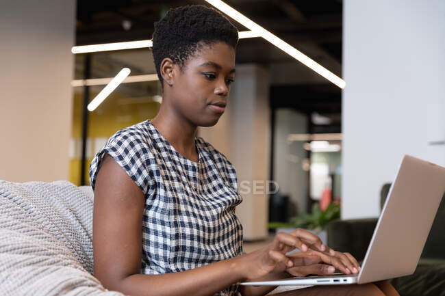 Geschäftsfrau mit gemischter Rasse sitzt mit Laptop in einem modernen Büro. Business moderne Büroarbeitstechnologie. — Stockfoto
