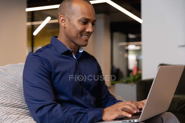 Змішаний гоночний бізнесмен сидить за допомогою ноутбука в сучасному офісі. бізнес сучасні технології офісного робочого місця . — стокове фото