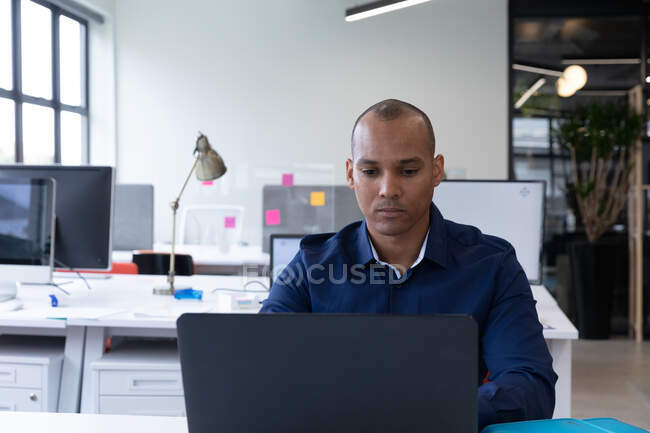 Uomo d'affari di razza mista seduto con un computer portatile in un ufficio moderno. affari ufficio moderno tecnologia sul posto di lavoro. — Foto stock