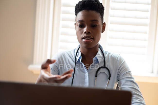 Африканская американка-врач делает видеоконсультацию с помощью ноутбука. телемедицина во время самоизоляции в карантинной изоляции. — стоковое фото