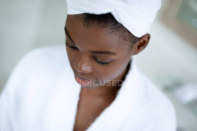 Close up view of african american woman in bathrobe in bathroom at home. staying at home in self isolation in quarantine lockdown — Stock Photo