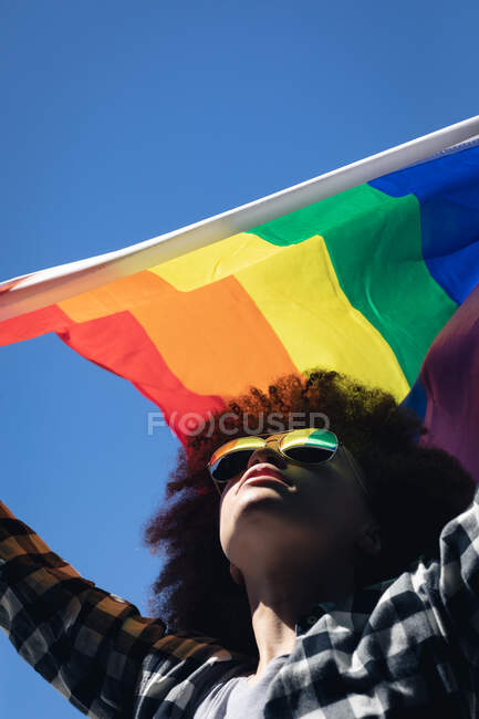 Mulher de raça mista em pé no telhado segurando bandeira do arco-íris. gênero fluido lgbt identidade conceito de igualdade racial. — Fotografia de Stock
